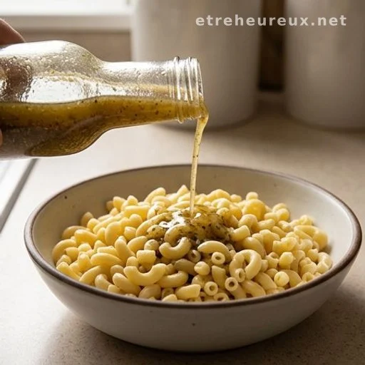 Italian dressing being poured over cooked elbow macaroni in a bowl
