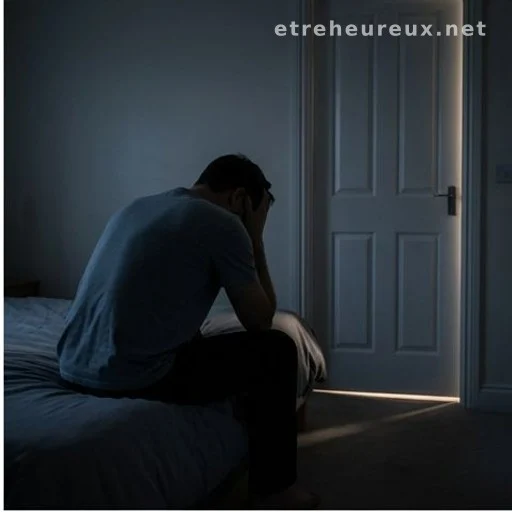Person sitting on bed edge in dark room, seen from behind, suggesting sleep distress