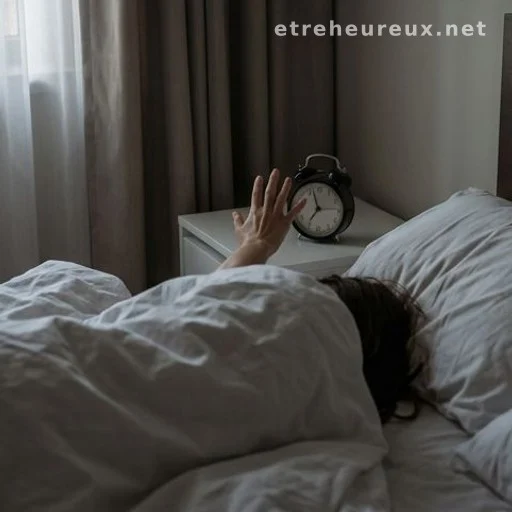 Hand reaching from unmade bed toward alarm clock in early morning light